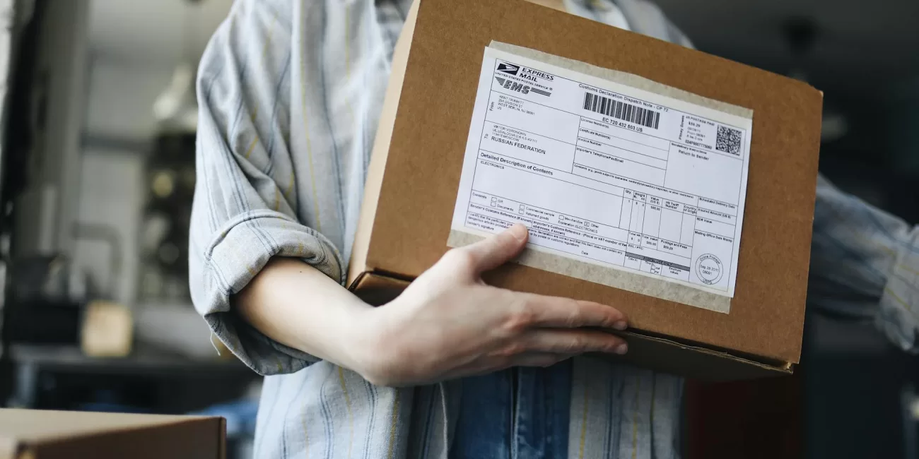 Persona sosteniendo una caja de cartón con una etiqueta de envío.